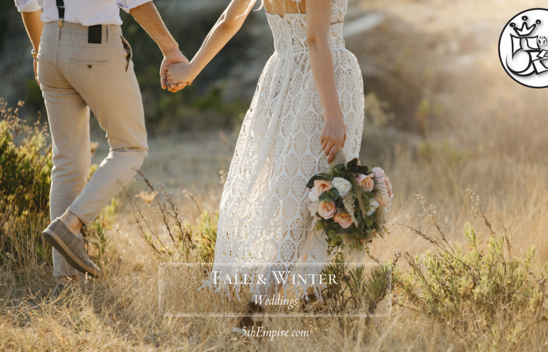 Couple walking hand in hand during the fall. Bride has a bouquet in hand.