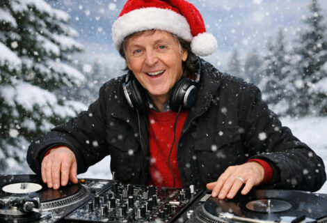 Paul McCartney wearing a Santa hat DJing on turntables in a snowy outdoor scene
